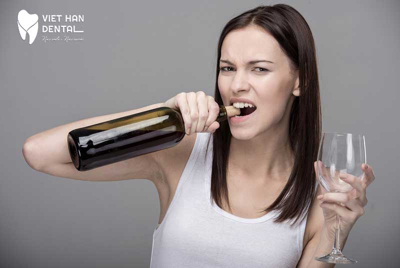 Người phụ nữ đang dùng răng để tháo nắp chai 